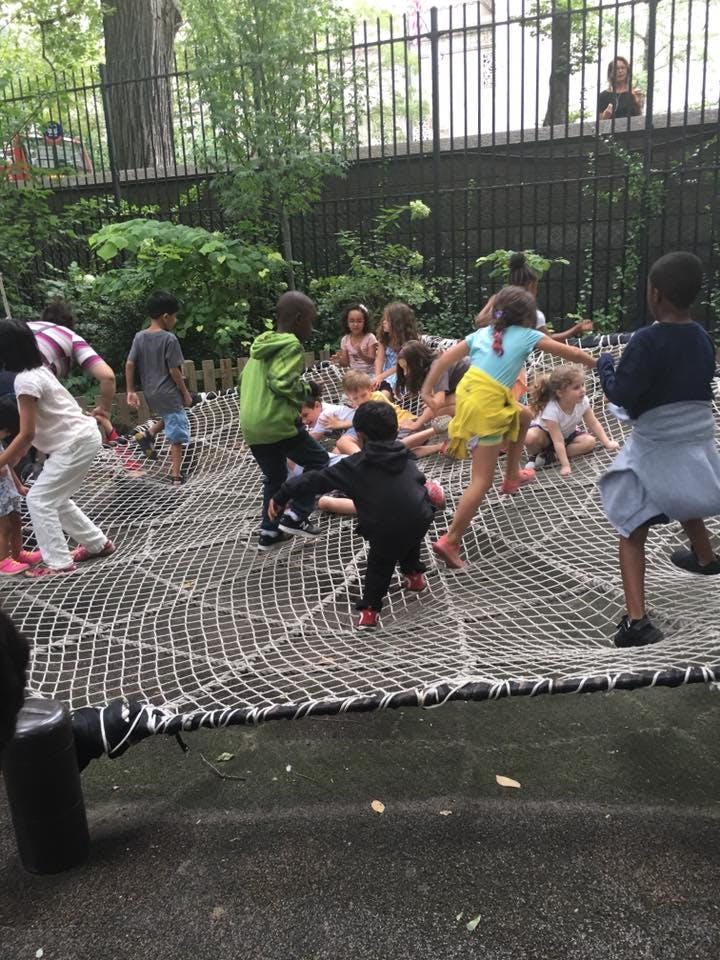 Children playing on a large rope net in a park