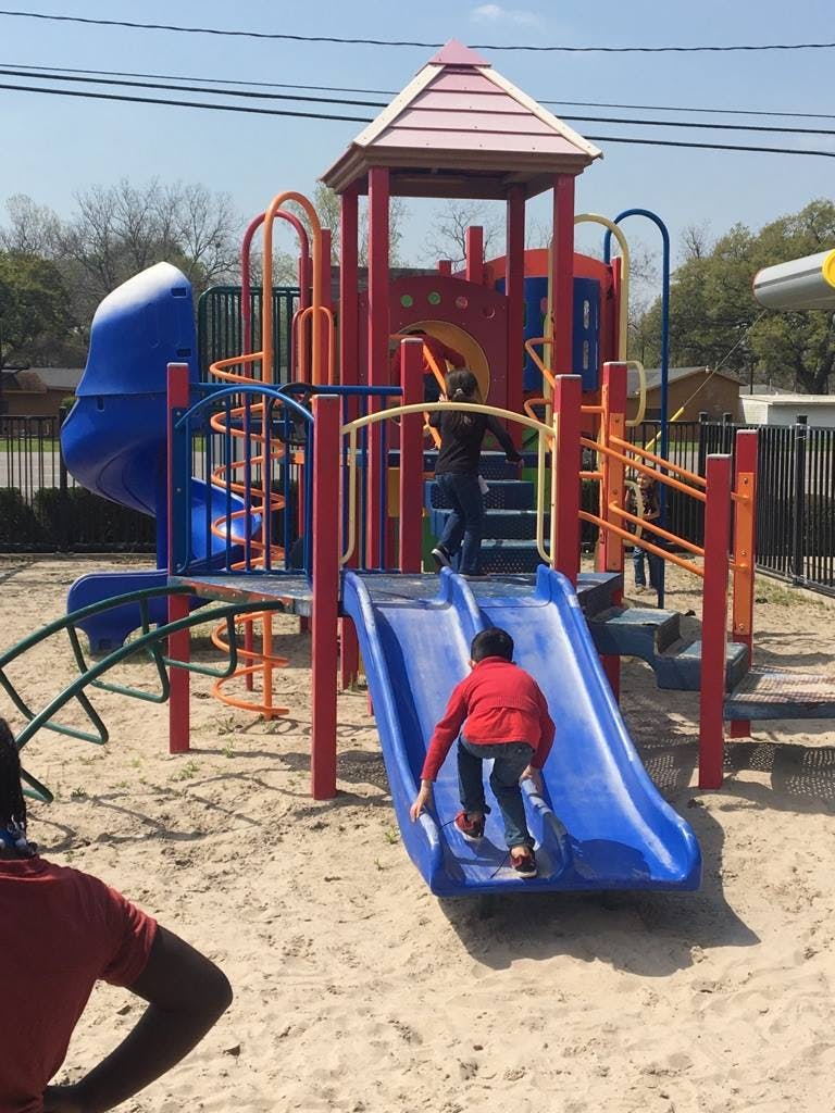 Child climbing up a blue slide on a playground structure