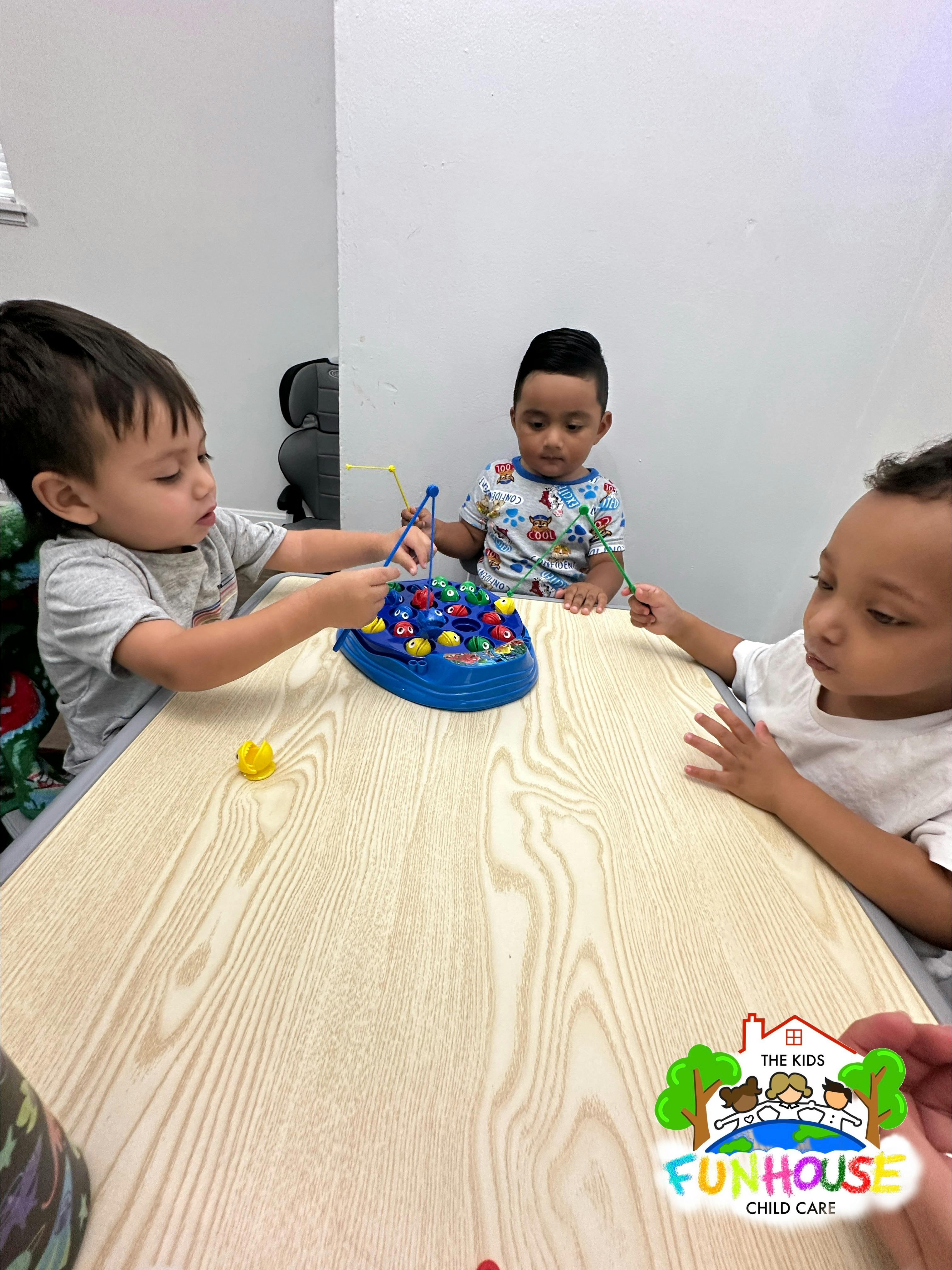Three children playing a fishing game at a table