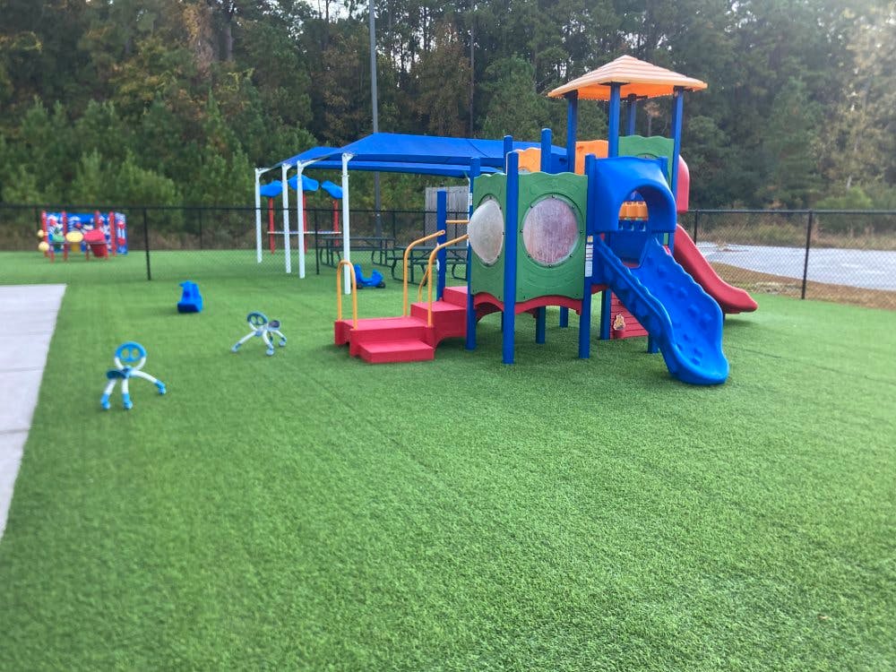 Colorful playground with slides and a covered area on artificial turf