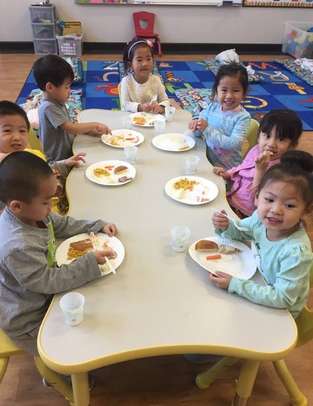 Children eating at a table in a classroom