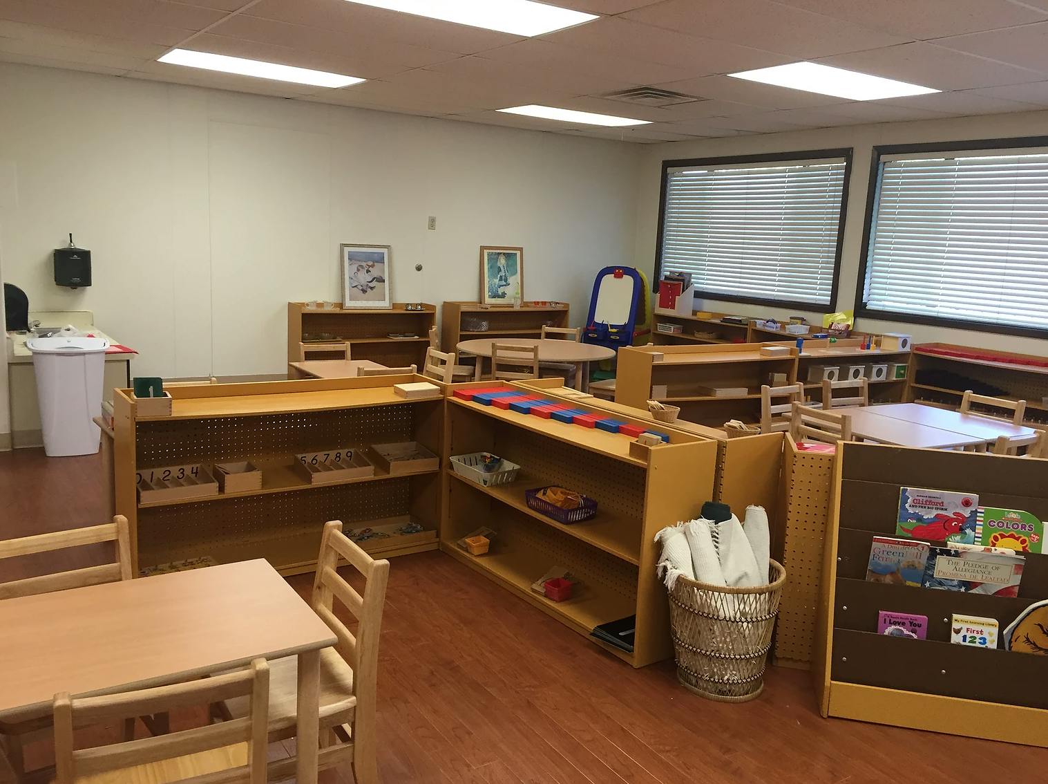 Classroom with small tables, chairs, and shelves filled with learning materials