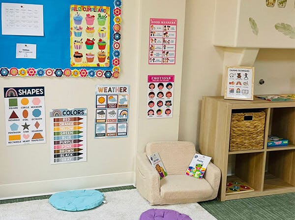 Classroom corner with an armchair, cubby shelf, and educational posters on the wall
