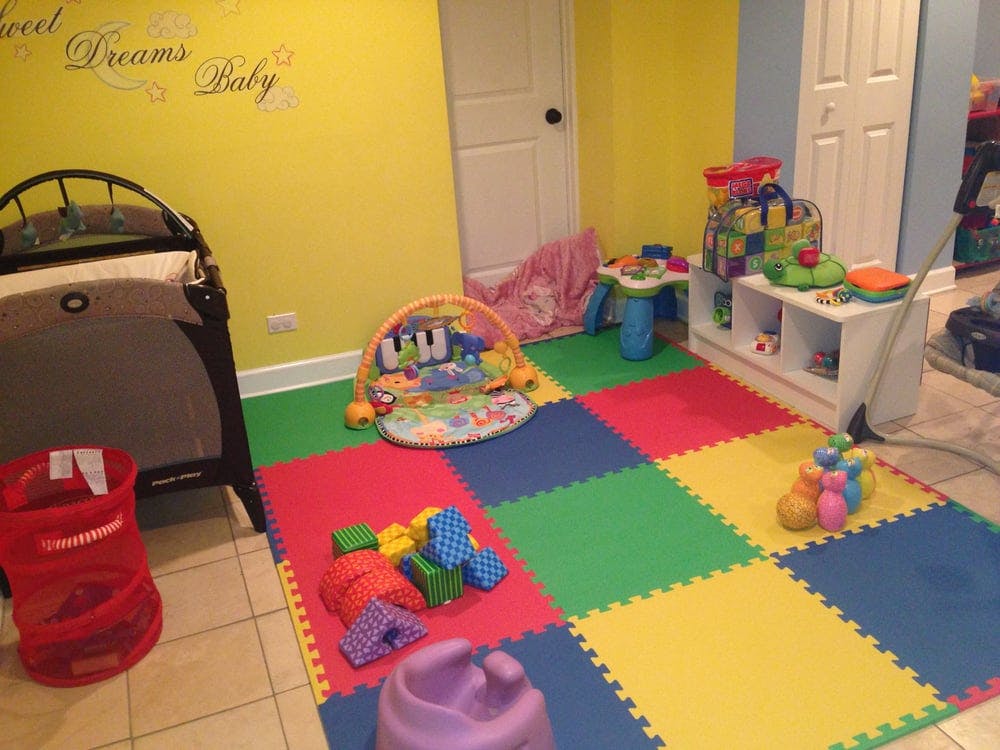 Playroom with colorful floor mats, crib, and various toys