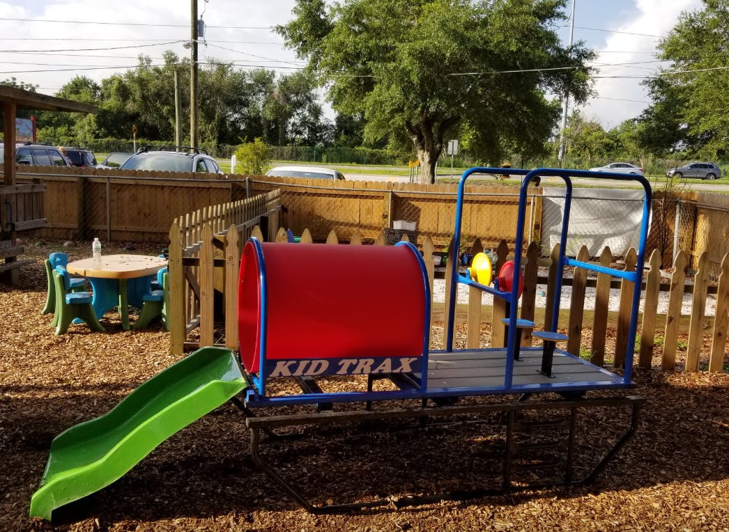 Playground with a red tunnel, green slide, and small table with chairs