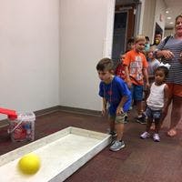 Child playing with a yellow ball on a ramp