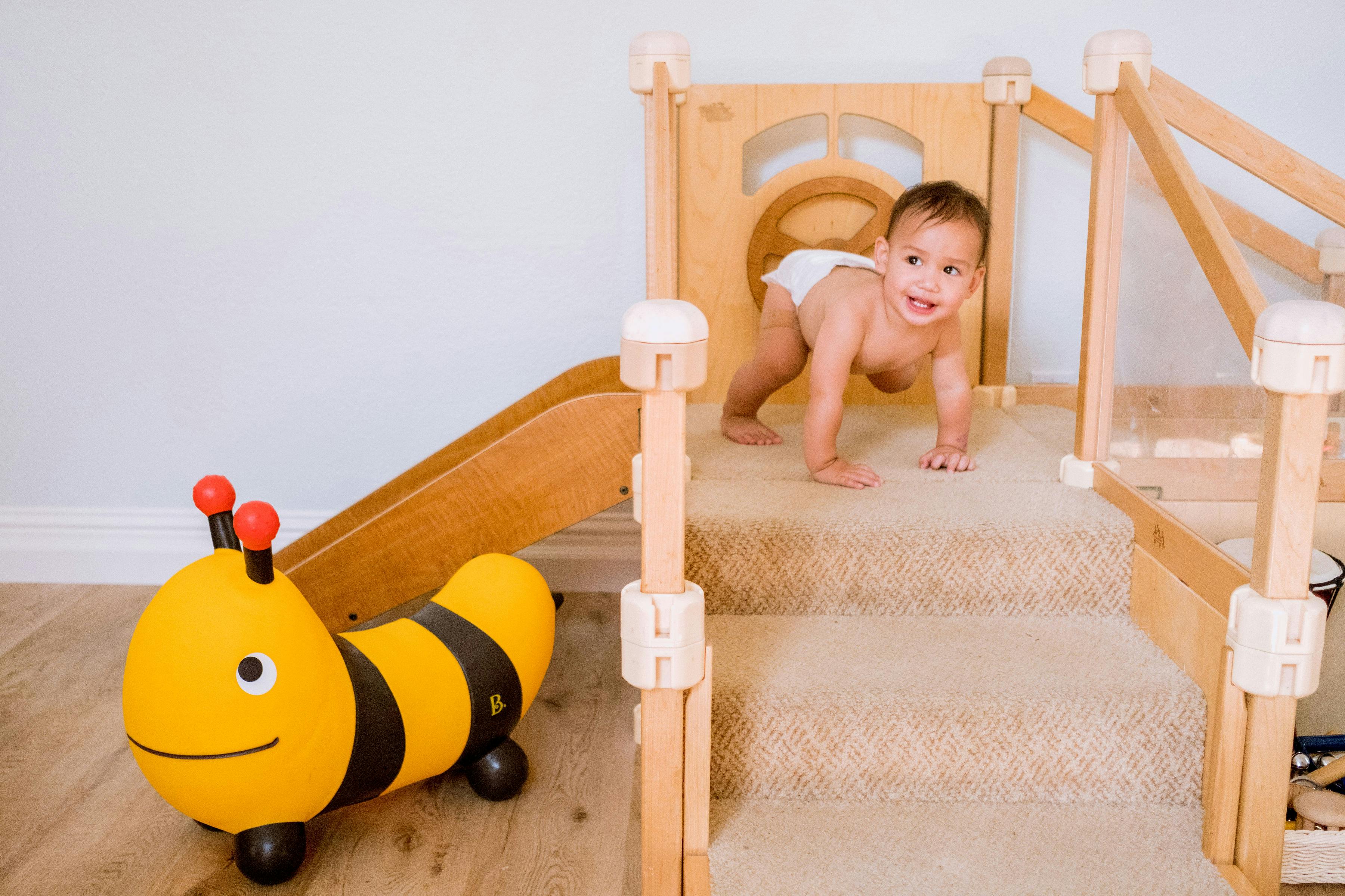 Child crawling on a play structure with a toy bee