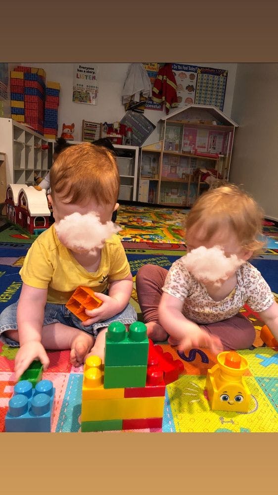 Two children playing with colorful building blocks on a mat
