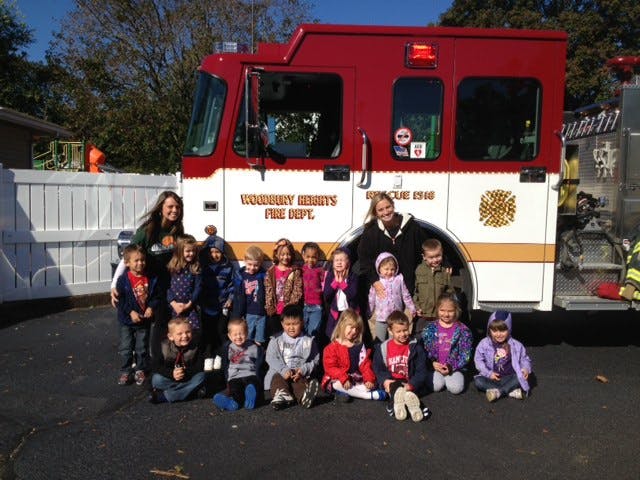 Two adults and a group of children posing in front of a fire truck