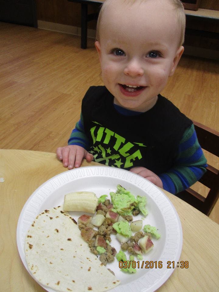 Child sitting at a table with a plate of food