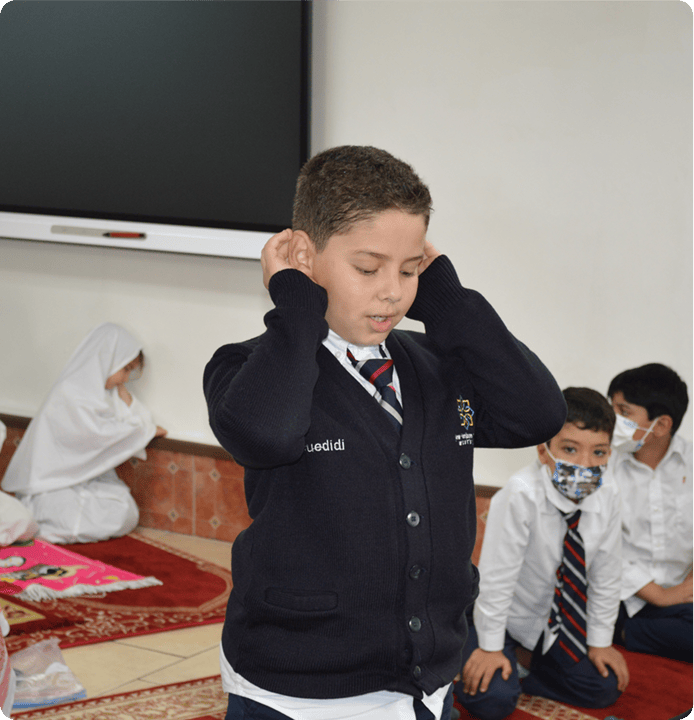 Child in uniform with hands to ears, two other children watching