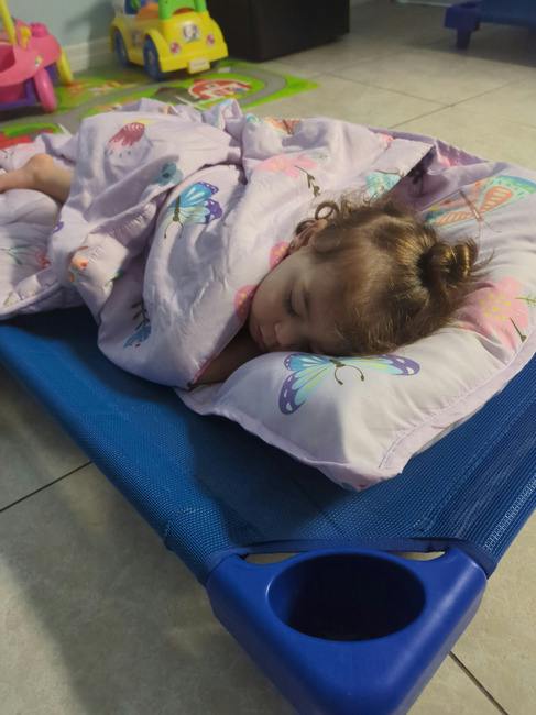 Child sleeping on a blue cot with a butterfly-patterned blanket