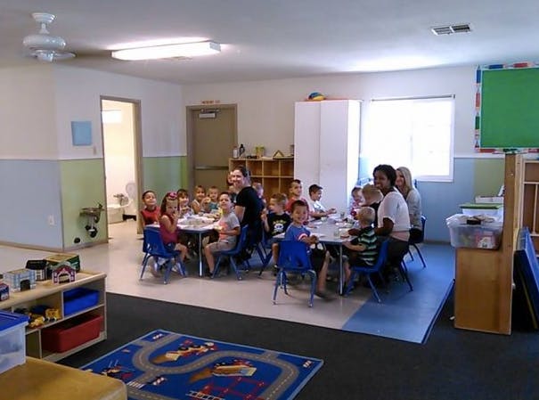 Adults and children sitting at tables in a classroom