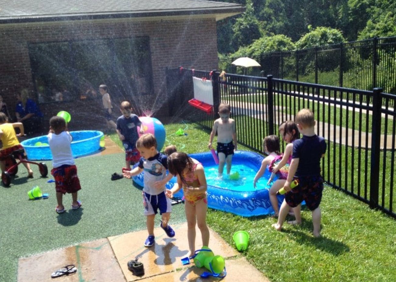 Children playing in sprinklers and wading pools outdoors