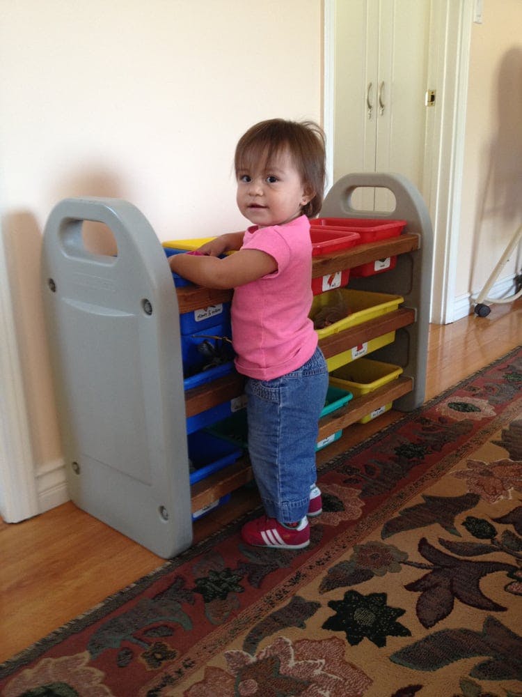 Child standing by a toy organizer