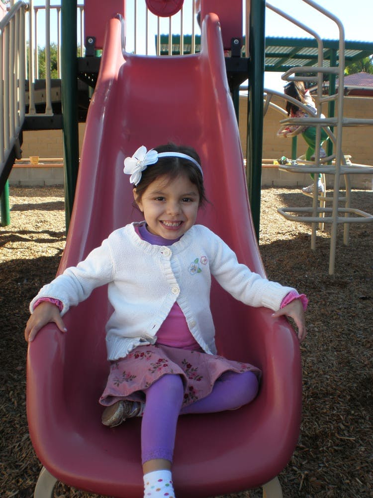 Child sitting on a red slide on a playground
