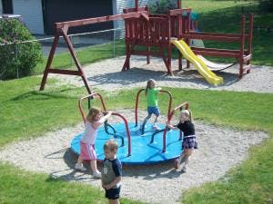 Children playing on a merry-go-round and playground equipment