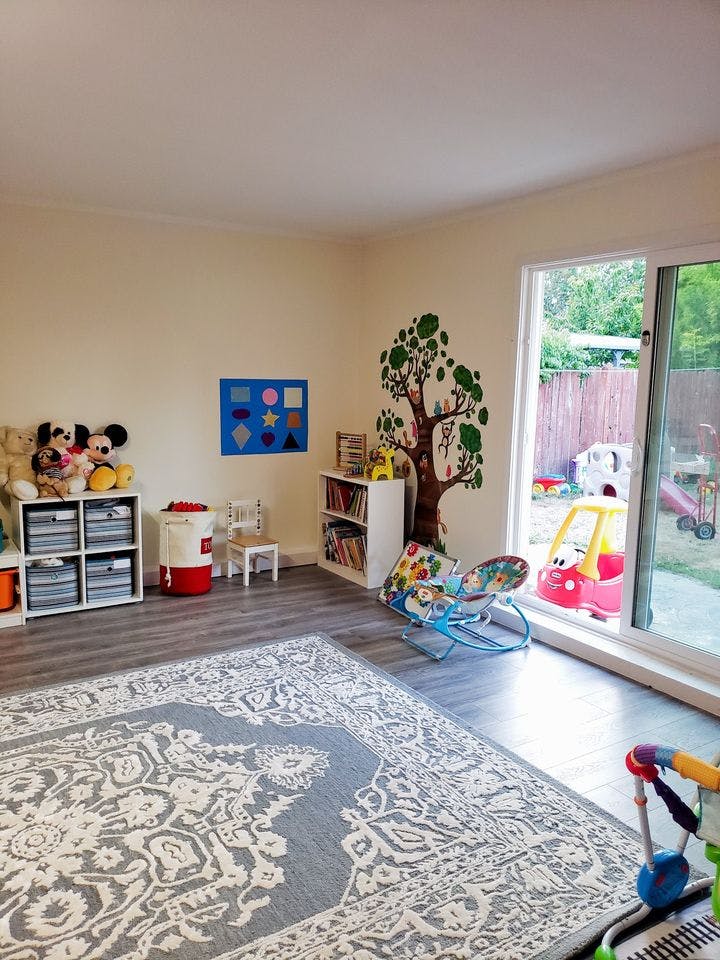 Playroom with toys, shelves, and a tree mural on the wall