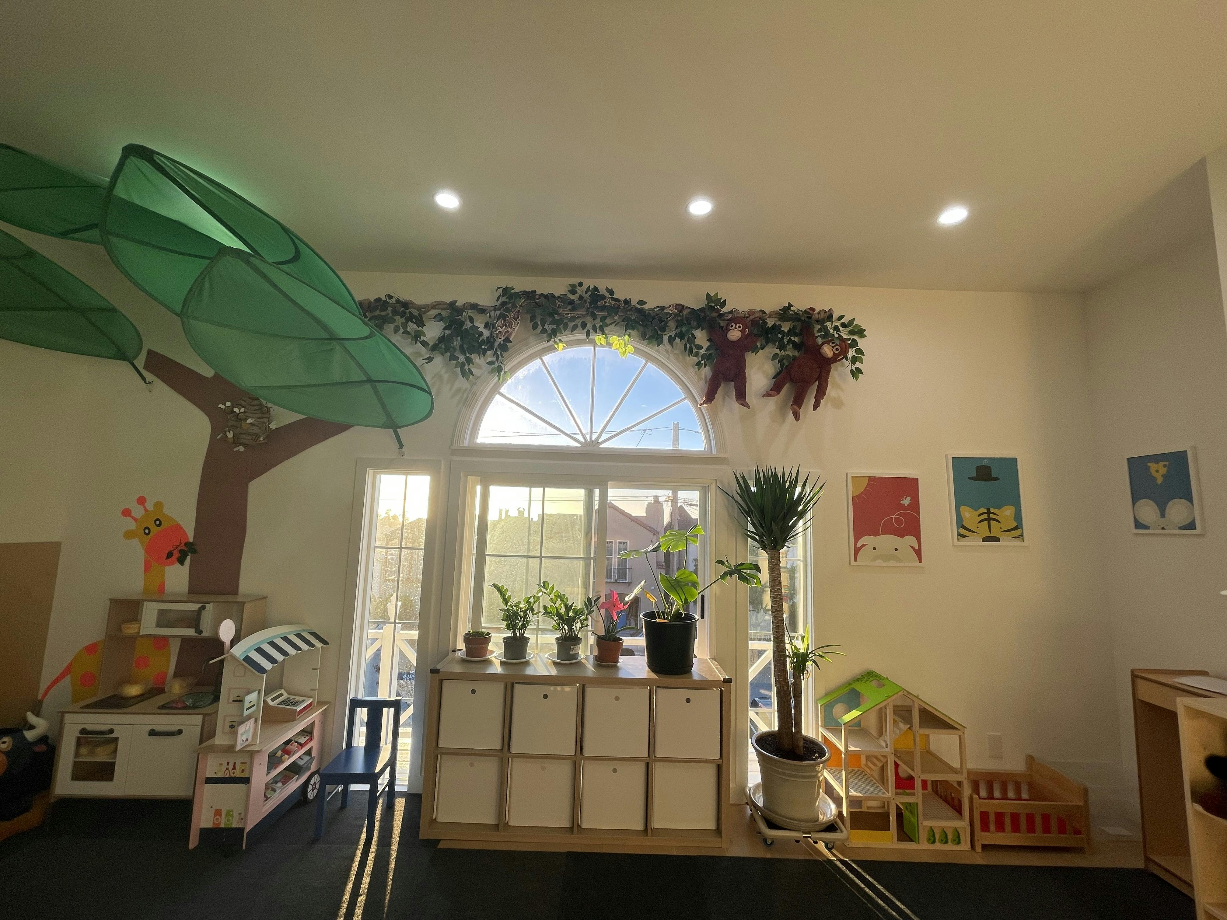 Playroom with a large window, plants, and play furniture