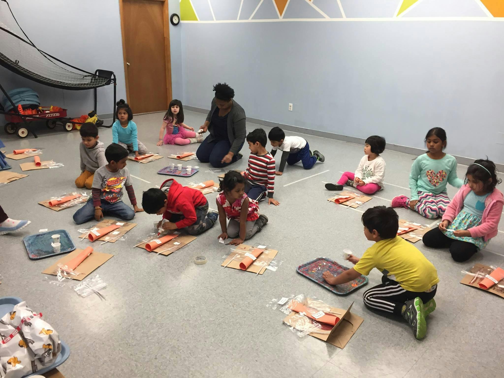 Adult and children sitting on the floor doing crafts