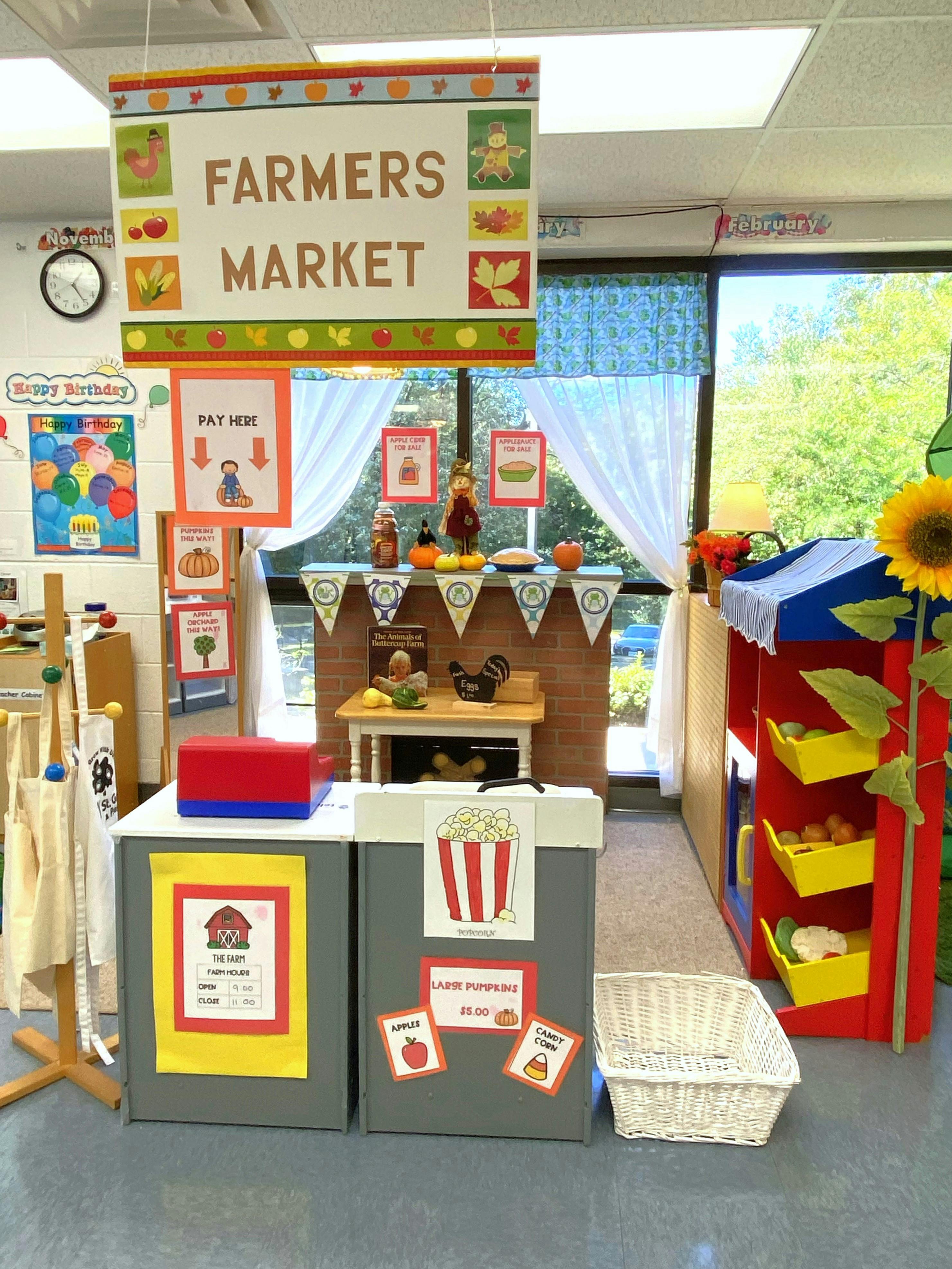 Classroom decorated as a farmers market with a sign that reads "FARMERS MARKET"