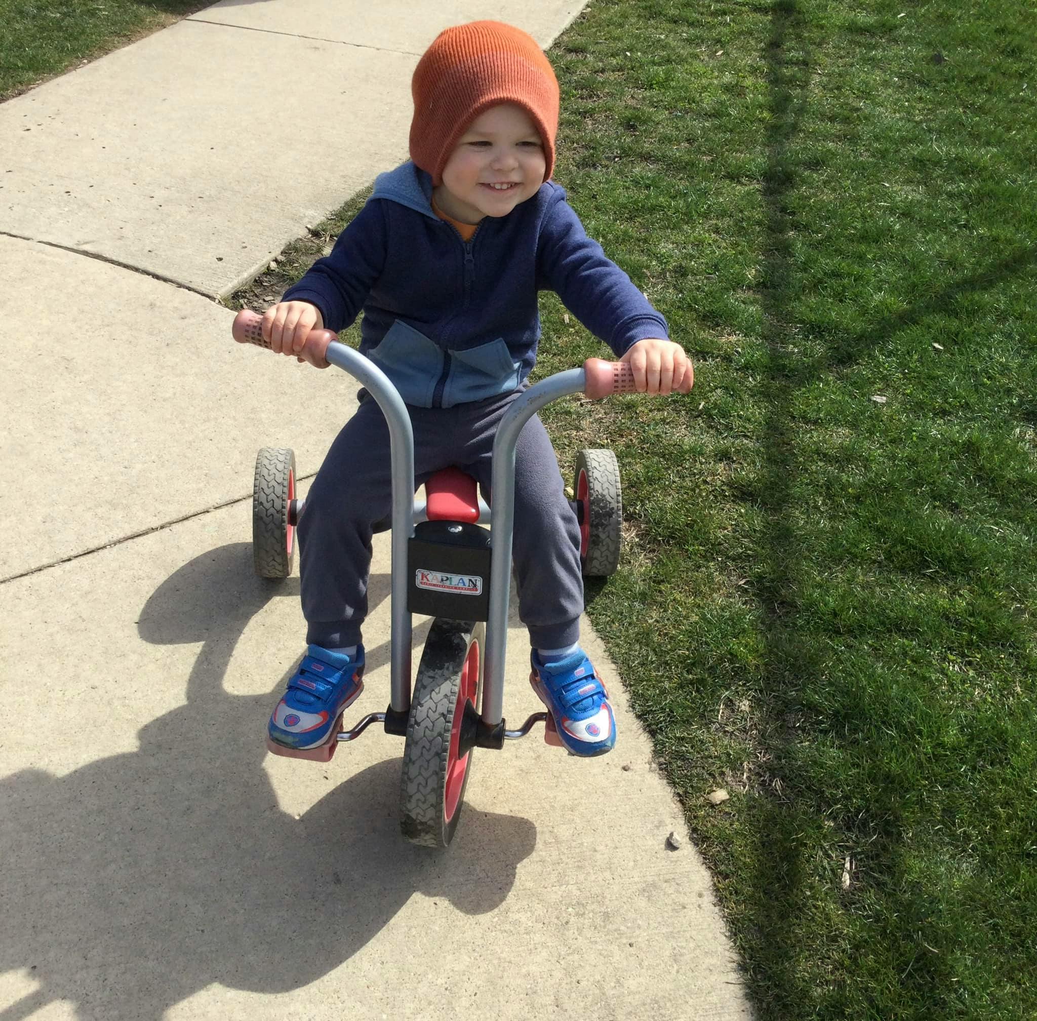 Child riding a tricycle on a sidewalk
