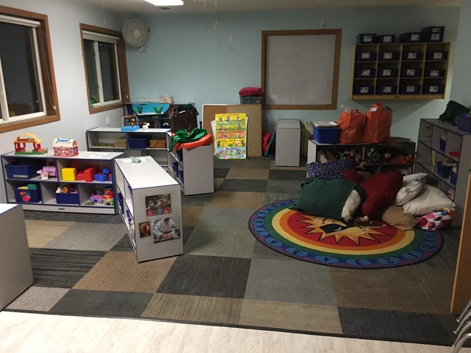 Classroom with shelves of toys and a colorful round rug