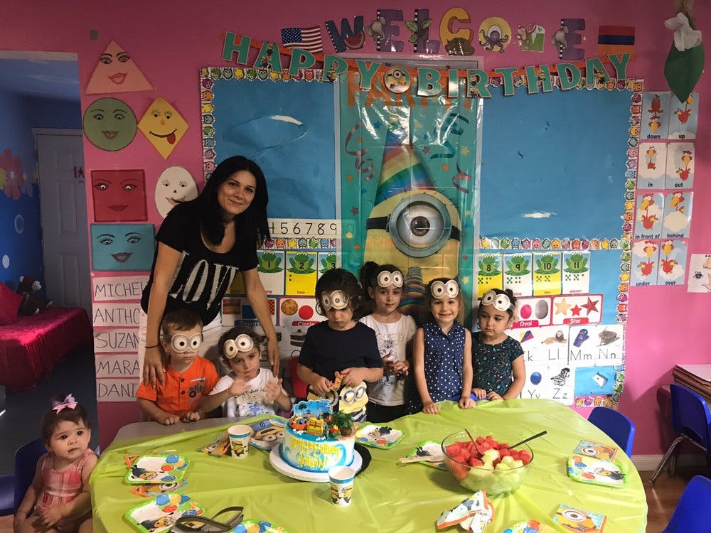 Person and children gathered around a table with a cake