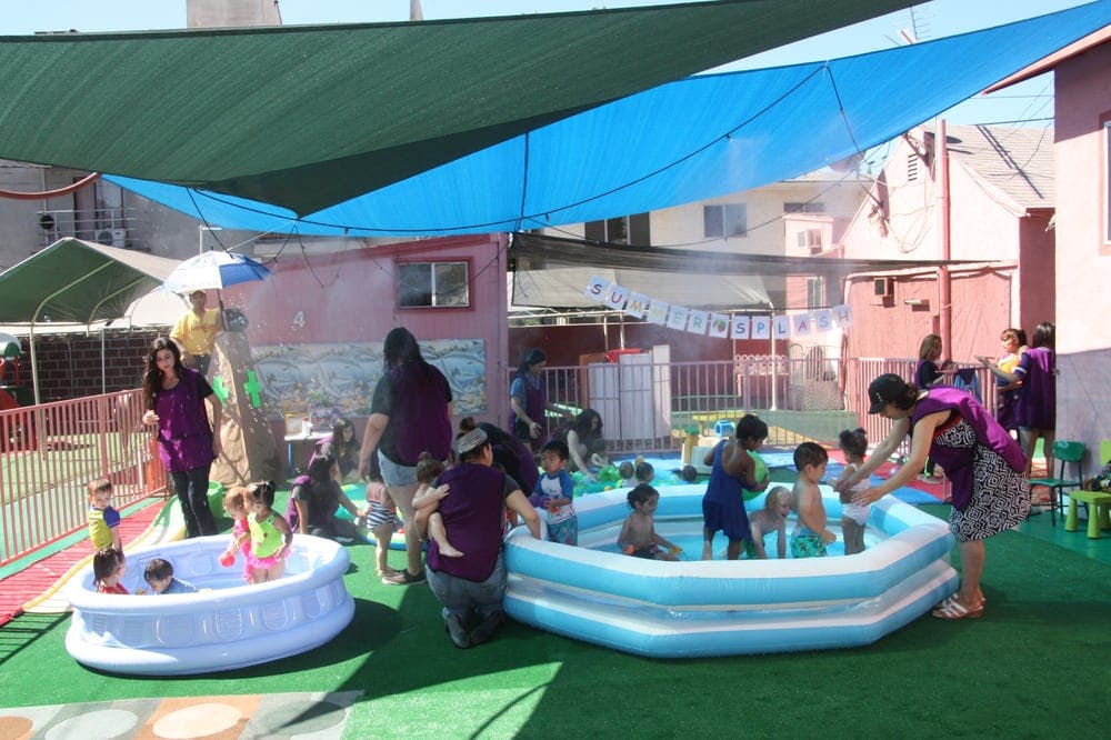 People and children playing in two inflatable pools outdoors