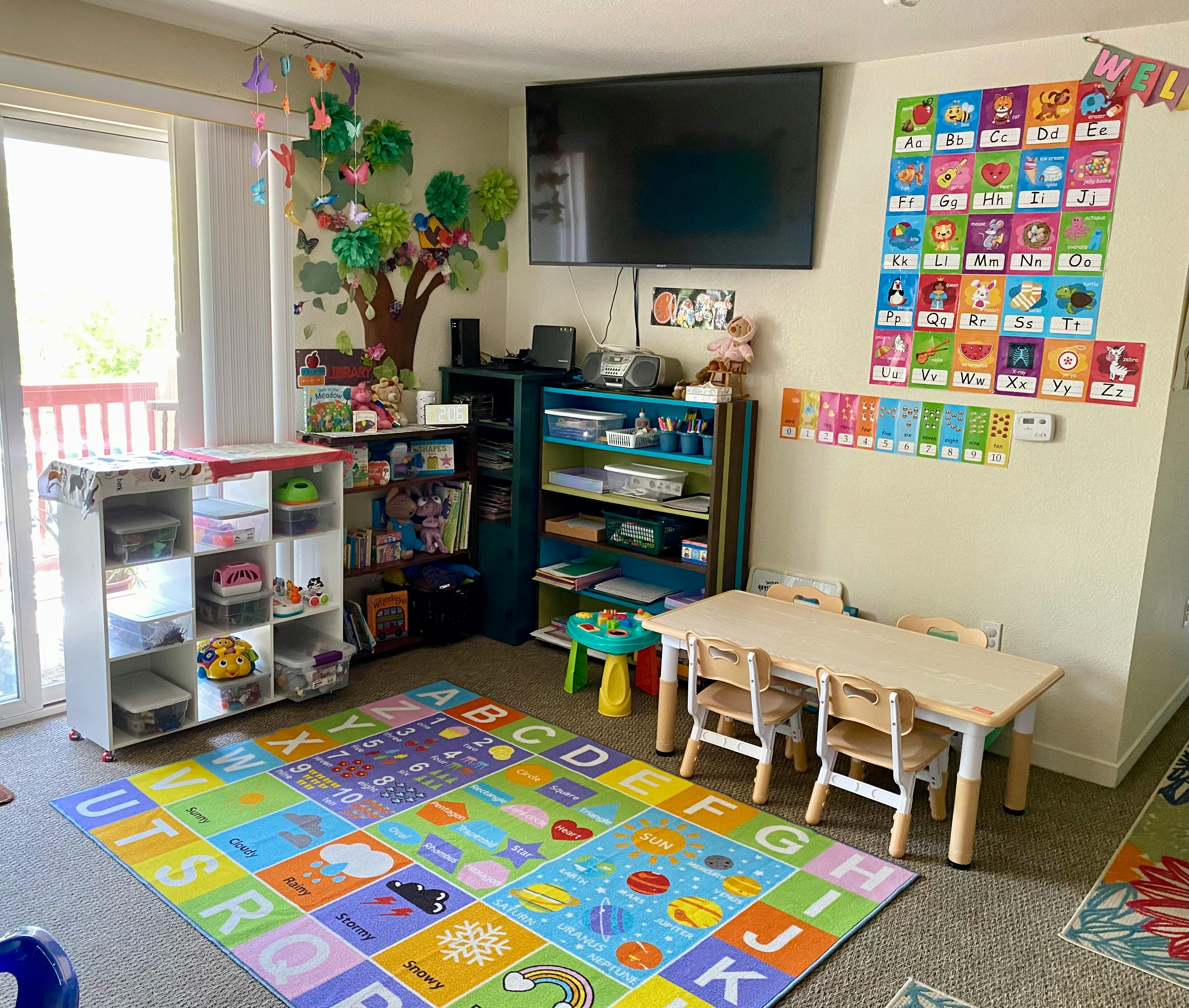 Child's classroom with colorful alphabet and number charts, play rug, and small table and chairs