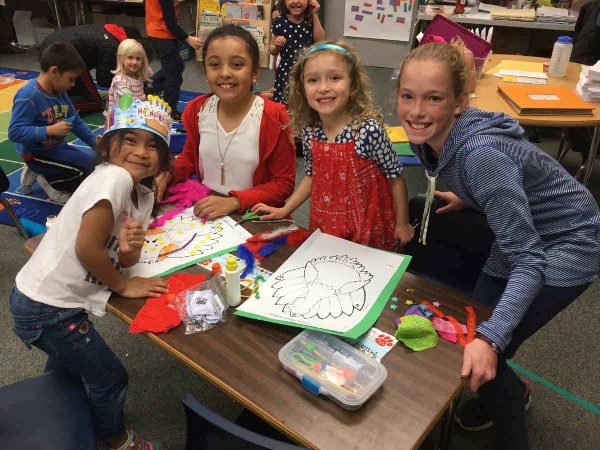 Four children at a table with art supplies and drawings