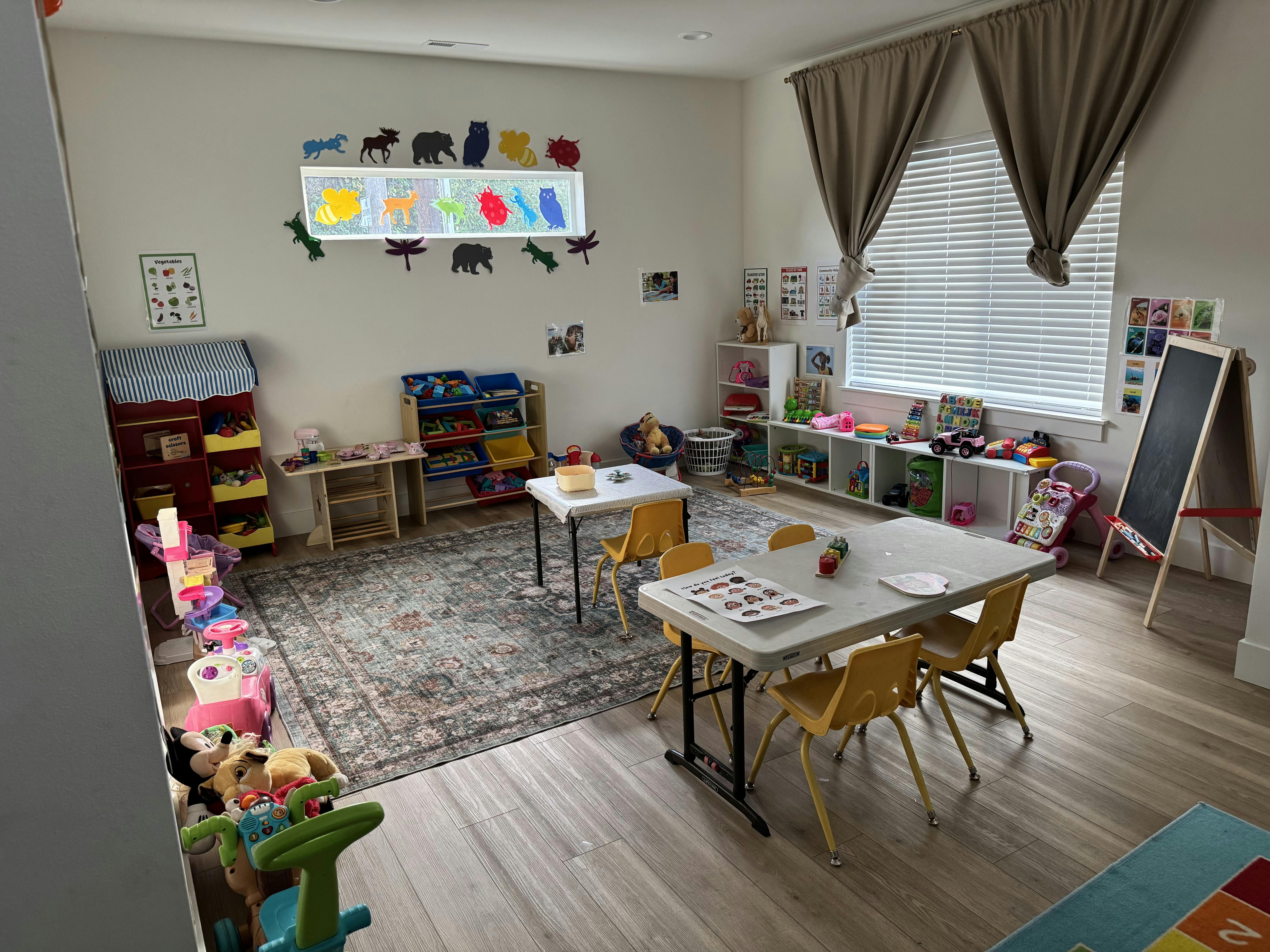 A playroom with children's tables, chairs, toys, and educational posters on the walls