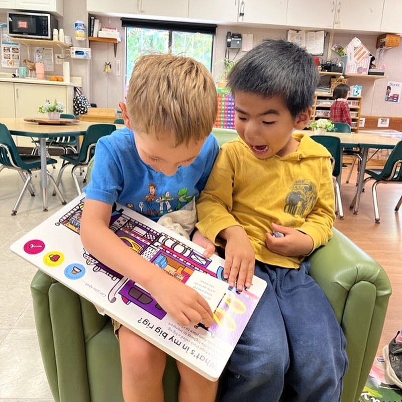 Two children sitting together and looking at a book