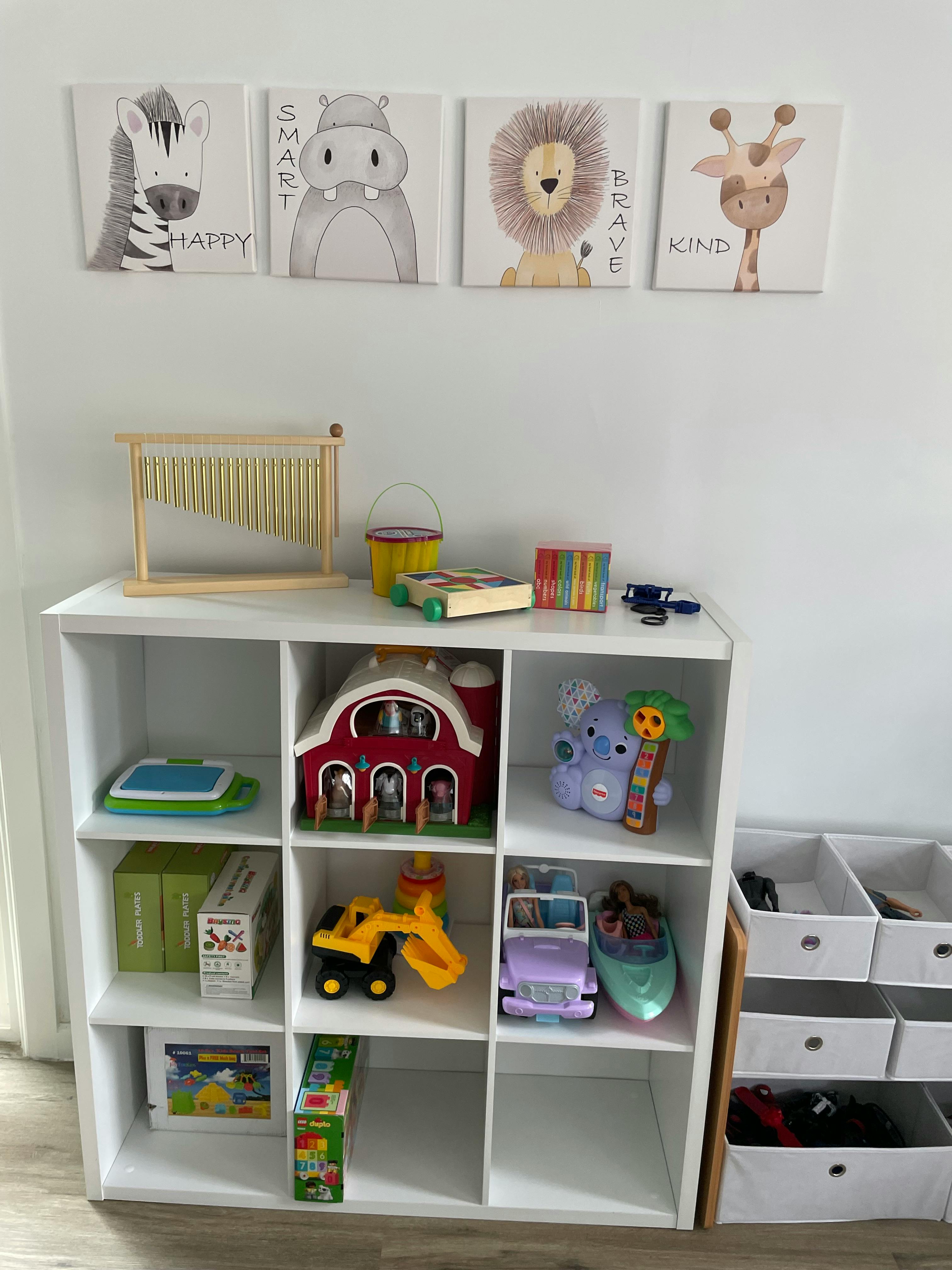 White shelving unit with toys and animal-themed wall art