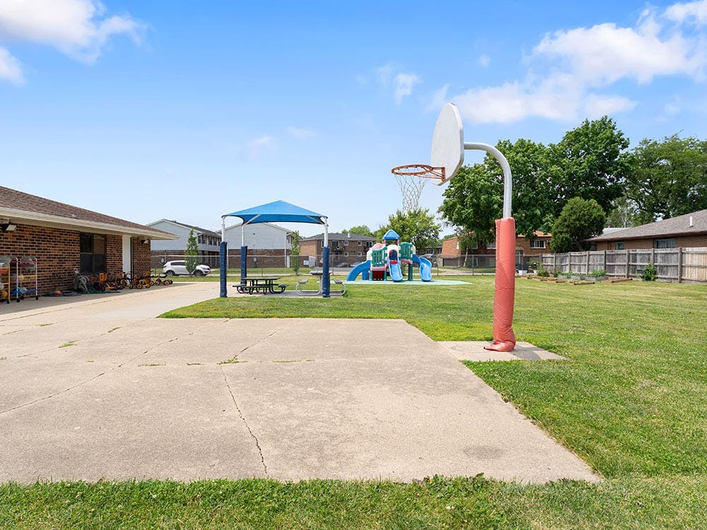Basketball hoop on a court next to a building and playground