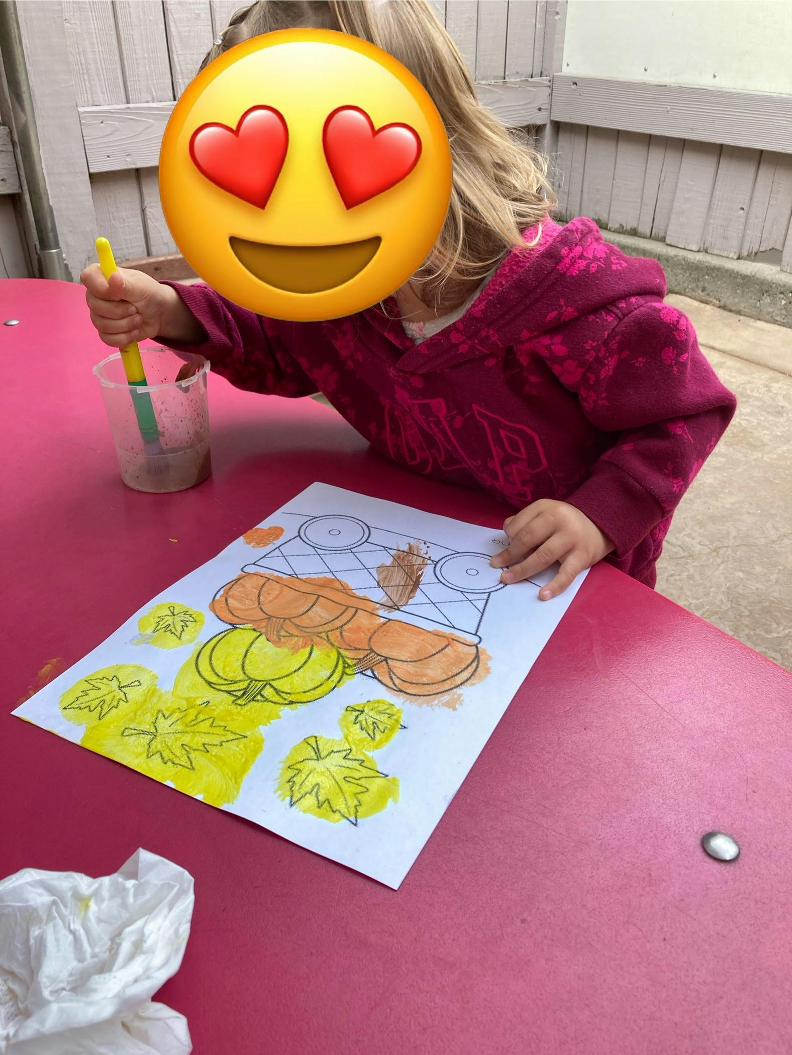 Child painting a picture of pumpkins and leaves