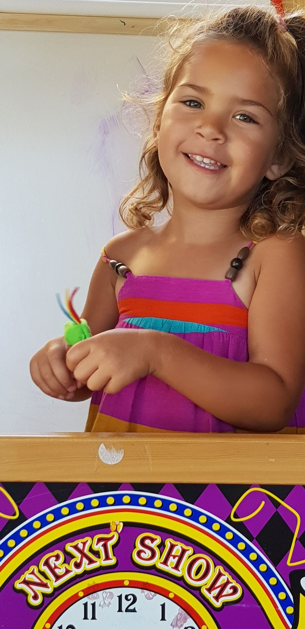 Child holding a toy with text "NEXT SHOW" visible below