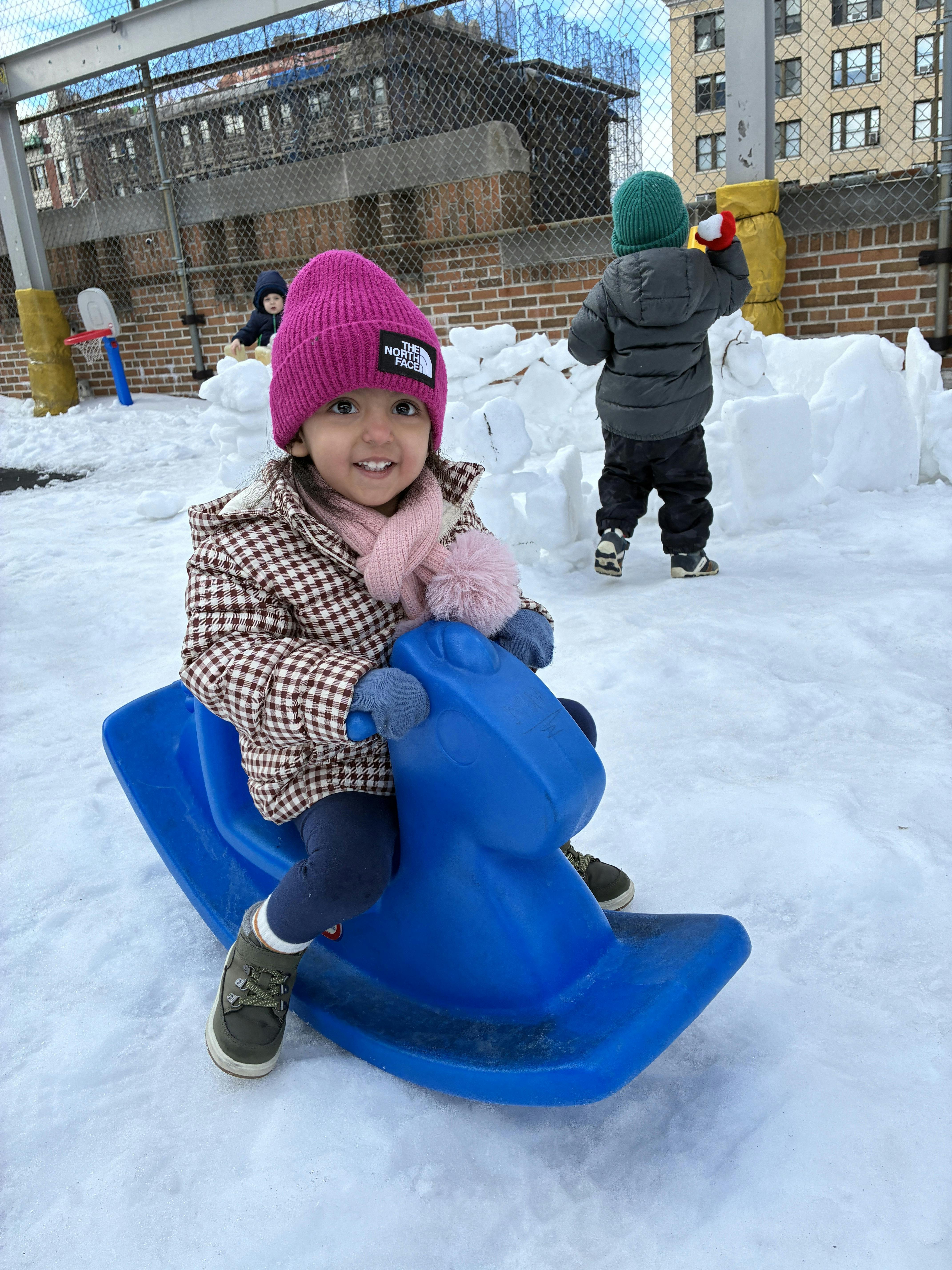 Child on a blue rocking horse in the snow