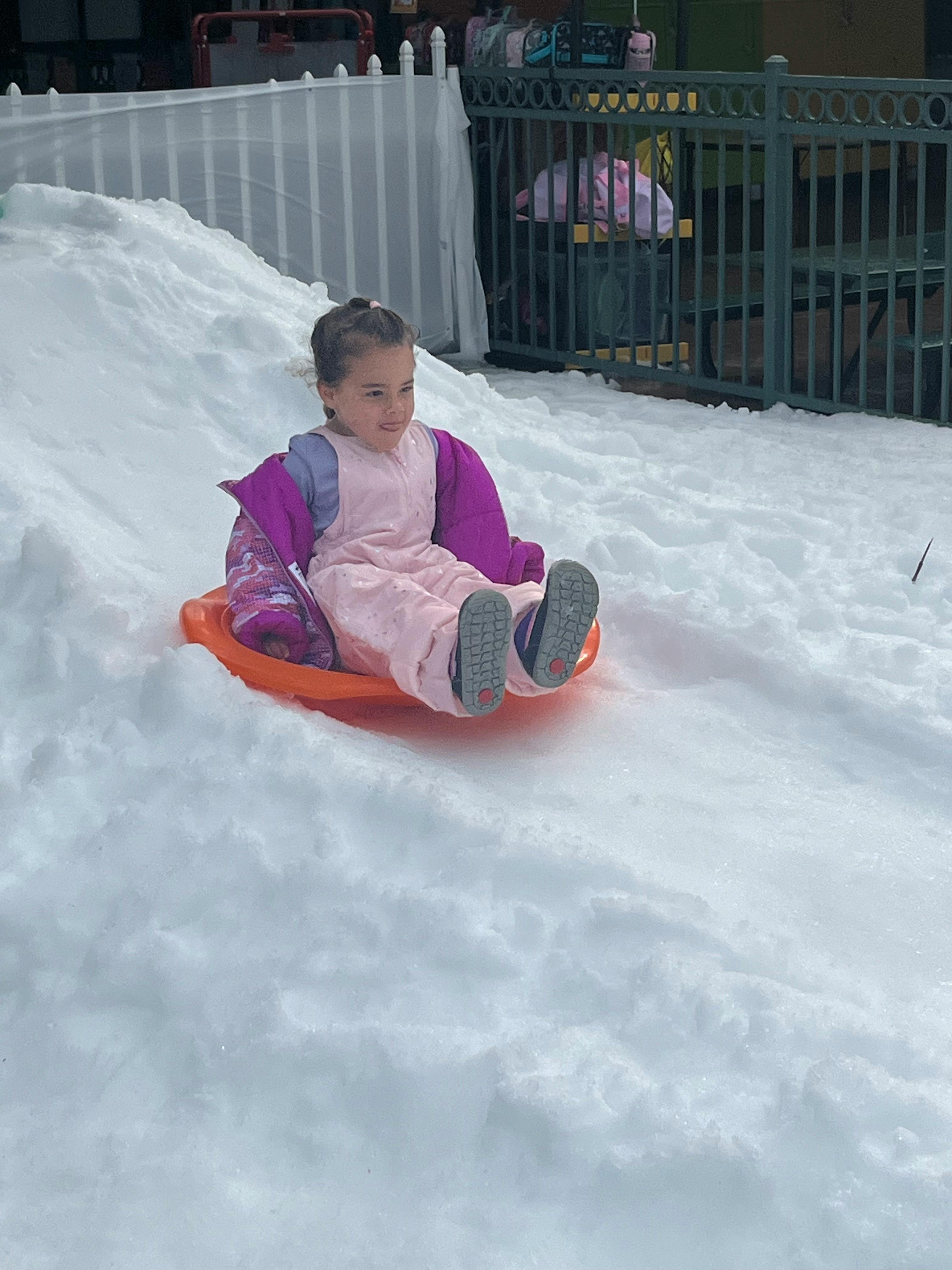 Child sledding down a snowy hill