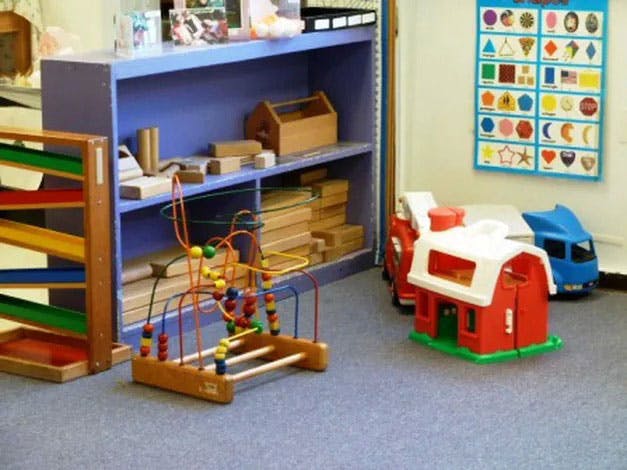 Playroom with a bead maze, toy barn, and blue shelving unit