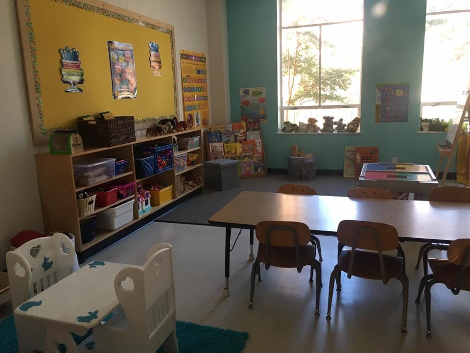 Classroom with tables, chairs, and shelves with shelves of learning materials