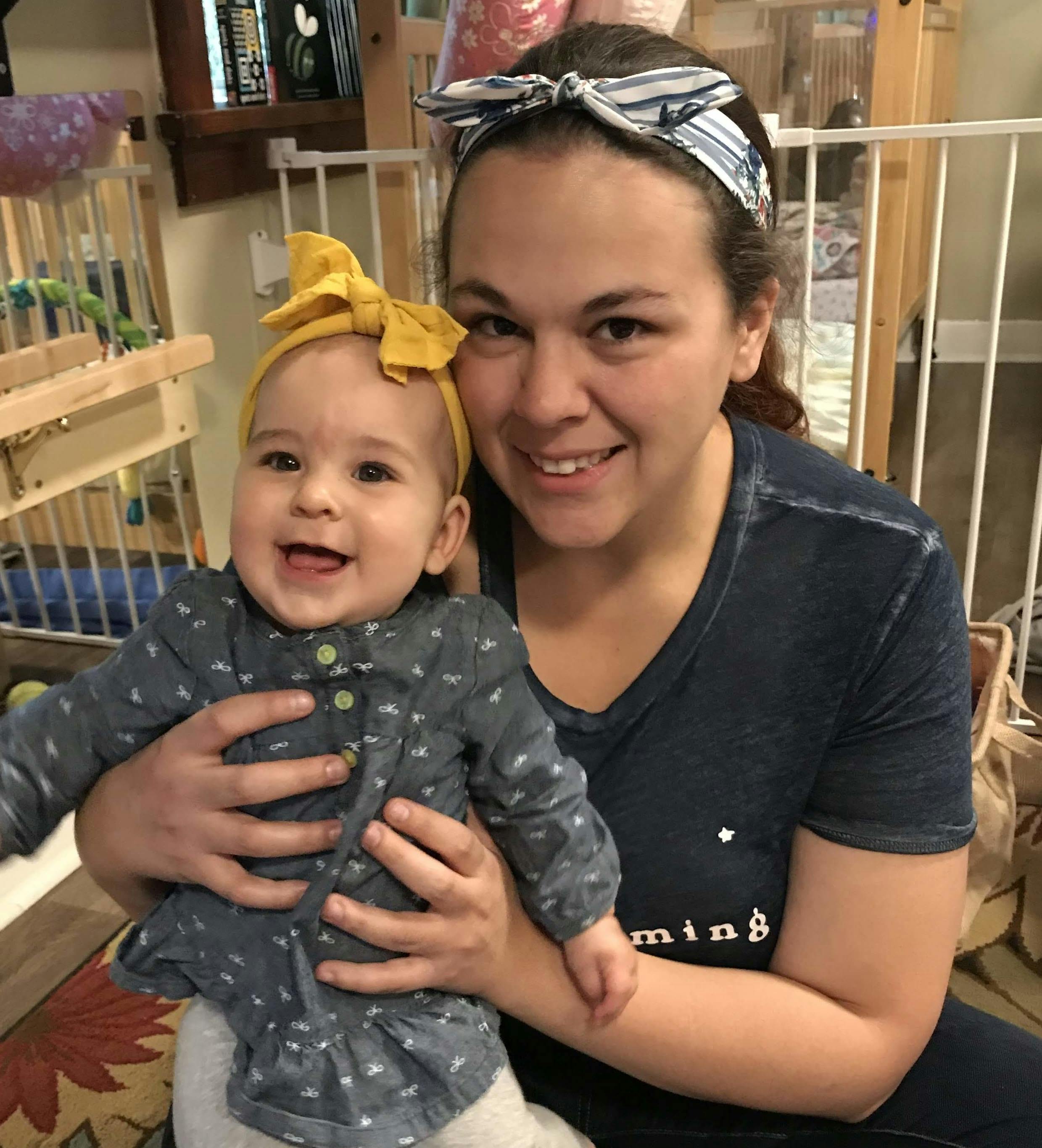 Person holding a child with a yellow bow headband
