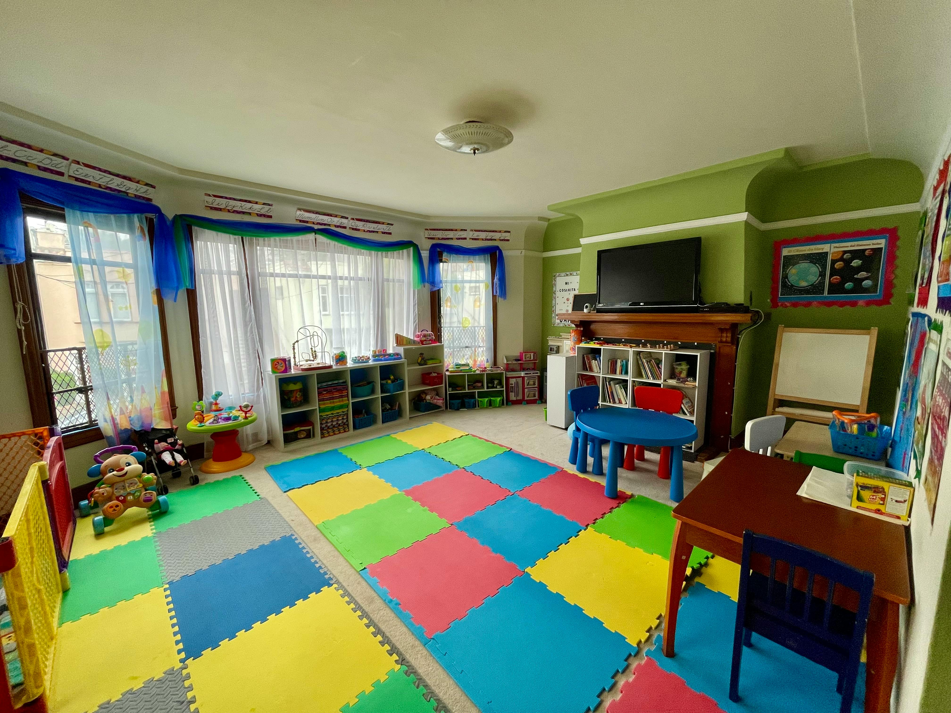 Playroom with colorful floor mats, shelves, and small tables