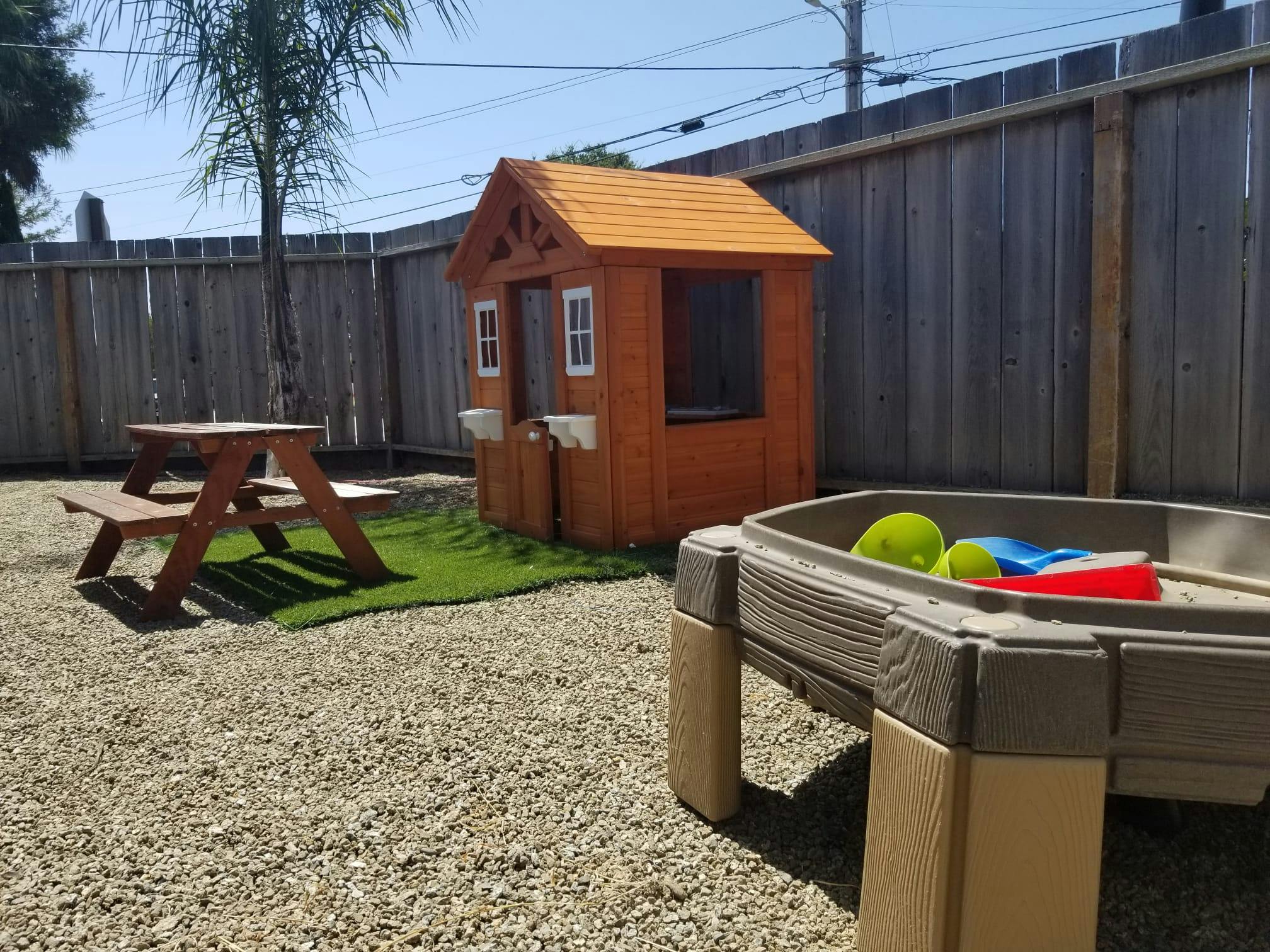 Playhouse, picnic table, and sand table in a backyard