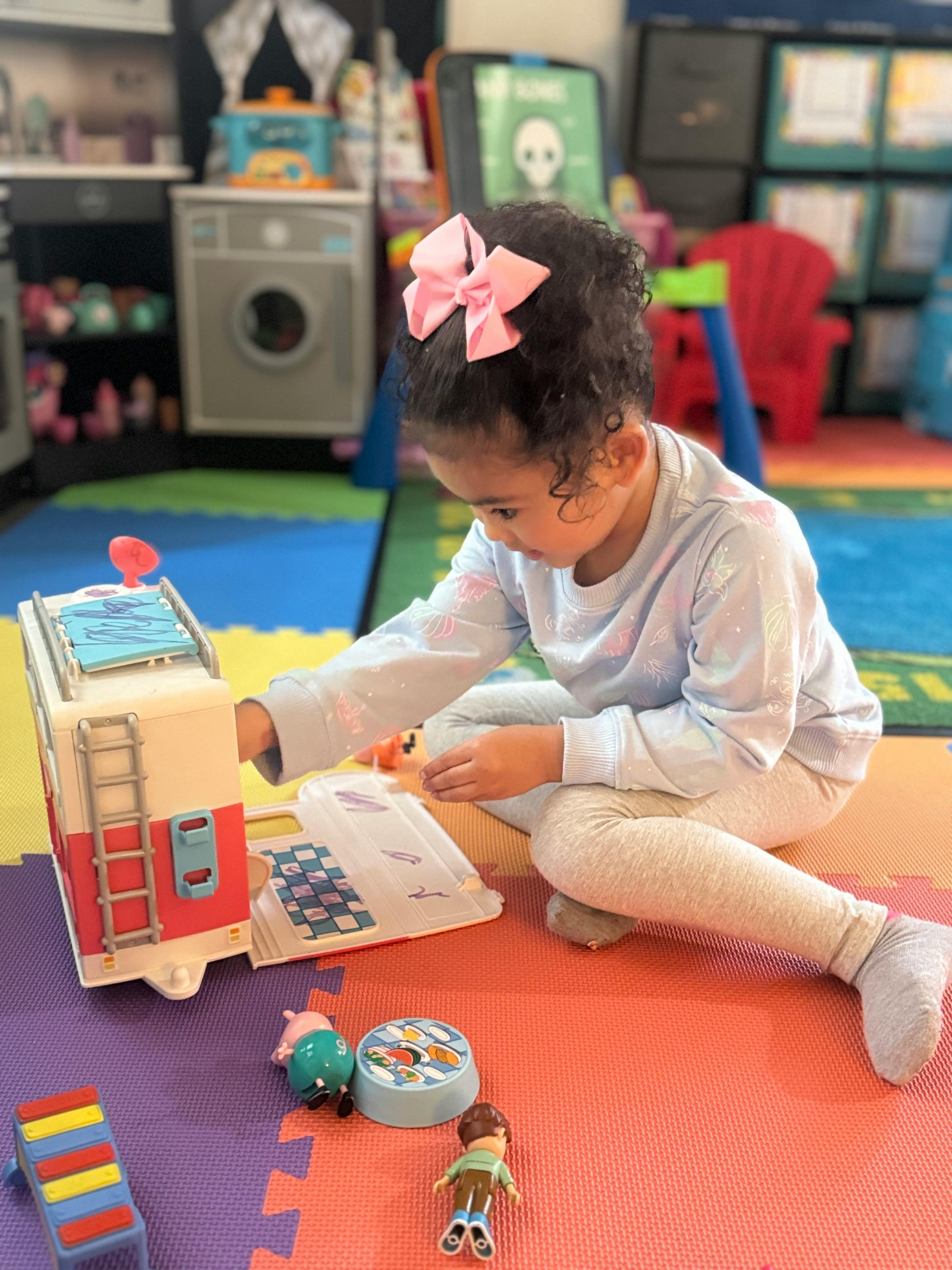 Child playing with a toy fire truck on a colorful mat