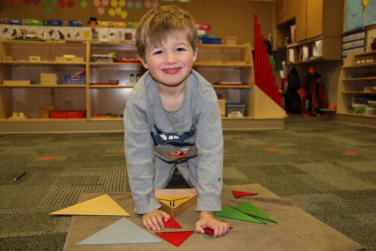 Child playing with colorful geometric shapes in a classroom