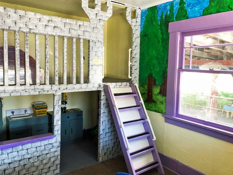 Playroom with castle-themed bunk bed and purple ladder