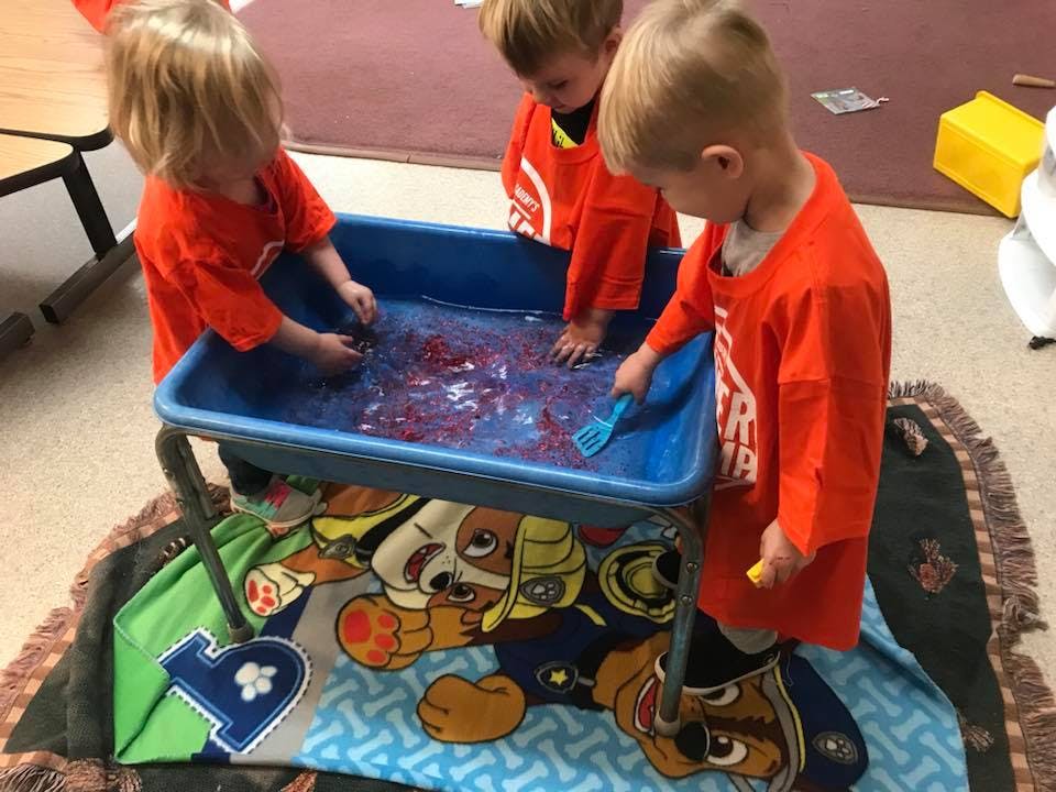 Three children playing with a water table