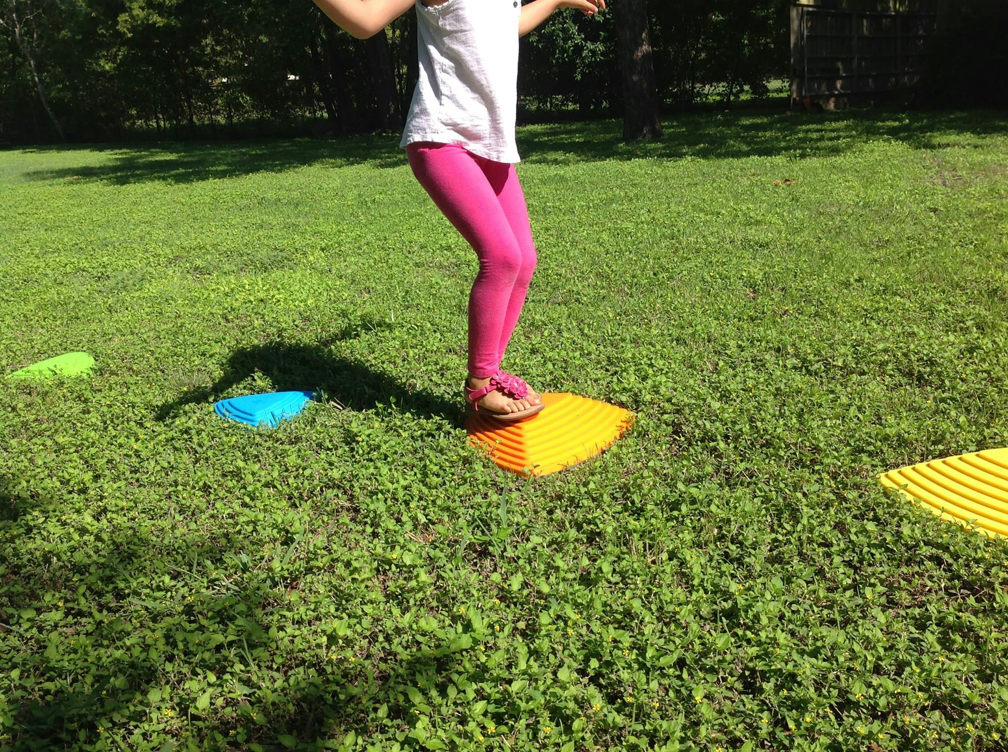 Child standing on a yellow mat in grass