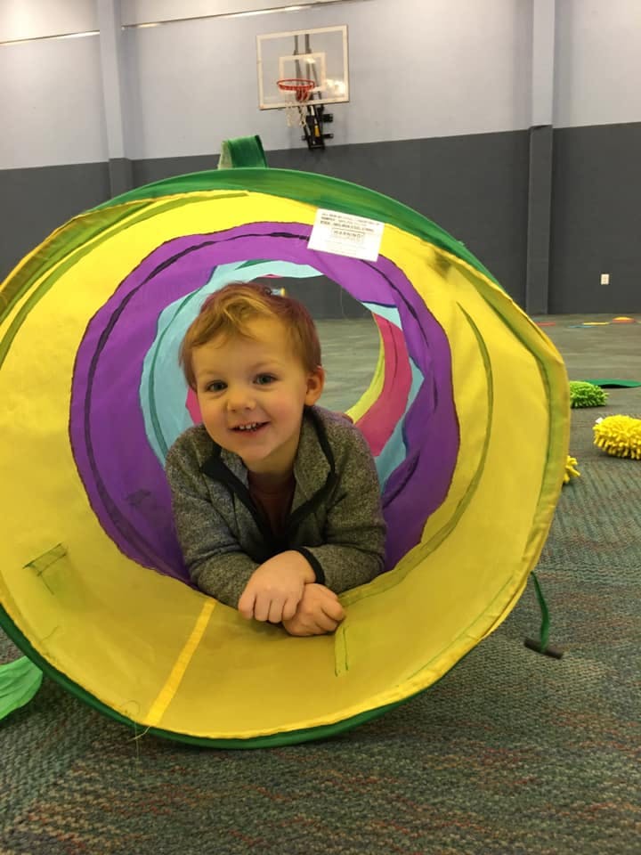 Child looking out of a colorful play tunnel